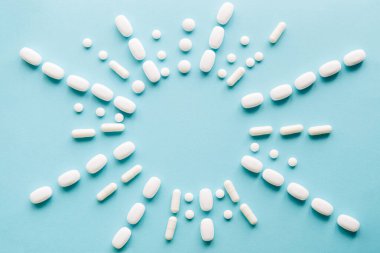 Mavi masaya saçılmış beyaz haplar. Reklam, web geçmişi ya da diğer fikirler için özel teklifler alın. Tıbbi, eczane ve sağlık hizmetleri konsepti. Uzayı kopyala Metin veya logo için boş yer