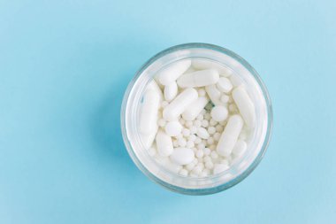 Mavi masaya saçılmış beyaz haplar. Reklam, web geçmişi ya da diğer fikirler için özel teklifler alın. Tıbbi, eczane ve sağlık hizmetleri konsepti. Uzayı kopyala Metin veya logo için boş yer