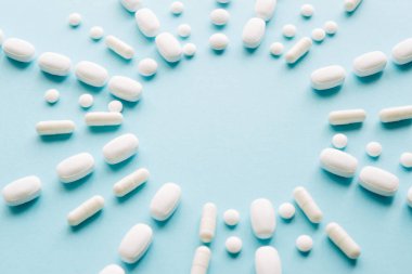 Mavi masaya saçılmış beyaz haplar. Reklam, web geçmişi ya da diğer fikirler için özel teklifler alın. Tıbbi, eczane ve sağlık hizmetleri konsepti. Uzayı kopyala Metin veya logo için boş yer
