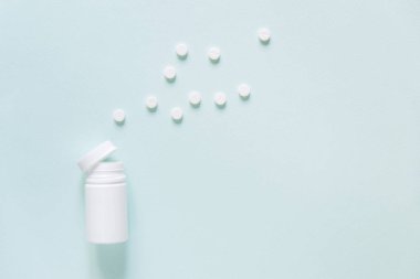 Mavi masaya saçılmış beyaz haplar. Reklam, web geçmişi ya da diğer fikirler için özel teklifler alın. Tıbbi, eczane ve sağlık hizmetleri konsepti. Uzayı kopyala Metin veya logo için boş yer