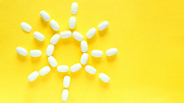 White pills on a yellow background. health care and medicine. Vitamin D. Vitamin for bright and positive emotions. Sun.