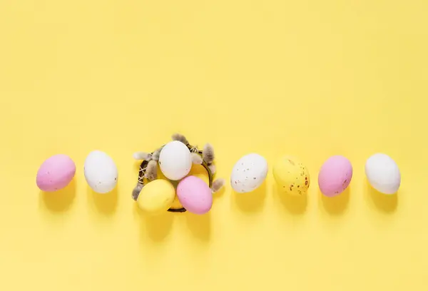 黄色の背景にキャンディイースターエッグと柳の枝の小さな花輪 幸せなイースターフラットレイアウト コピースペース — ストック写真