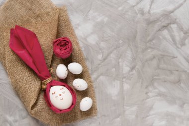 Decoration Happy Easter concept. Minimalism gift wrapping egg in the shape of a rabbit on a light gray background. Cute funny drawing on the egg. Copy space.