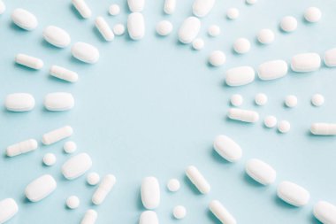 Mavi masaya saçılmış beyaz haplar. Reklam, web geçmişi ya da diğer fikirler için özel teklifler alın. Tıbbi, eczane ve sağlık hizmetleri konsepti. Uzayı kopyala Metin veya logo için boş yer