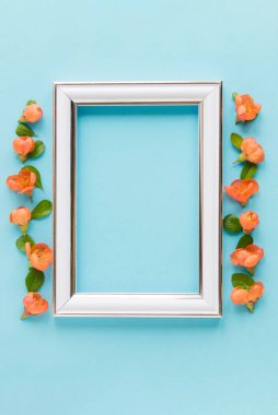 Blank white frame on a plain blue background. poster layout for art display. Top view, copy space. no people. Floral decor. Interior details.