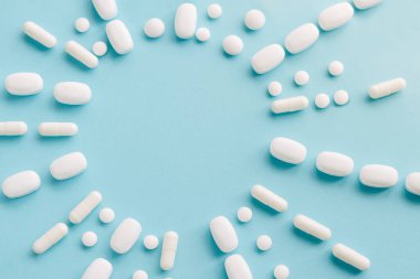 Mavi masaya saçılmış beyaz haplar. Reklam, web geçmişi ya da diğer fikirler için özel teklifler alın. Tıbbi, eczane ve sağlık hizmetleri konsepti. Uzayı kopyala Metin veya logo için boş yer