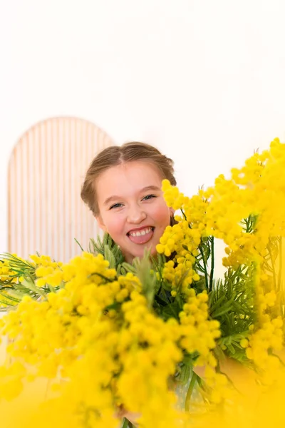 child gives flowers. portrait  little girl with a bouquet of yellow flowers.  girl in a blue dress. Bright interior.