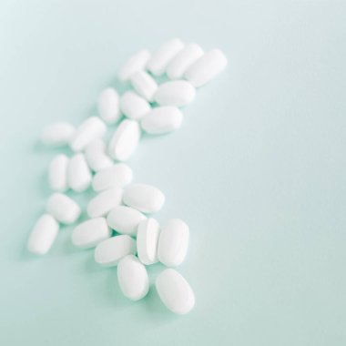 Mavi masaya saçılmış beyaz haplar. Reklam, web geçmişi ya da diğer fikirler için özel teklifler alın. Tıbbi, eczane ve sağlık hizmetleri konsepti. Uzayı kopyala Metin veya logo için boş yer