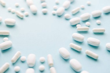 Scattered white pills on blue background. Mock up for special offers as advertising, web background or other ideas. Medical, pharmacy and healthcare concept. copyspace. Empty place for text or logo