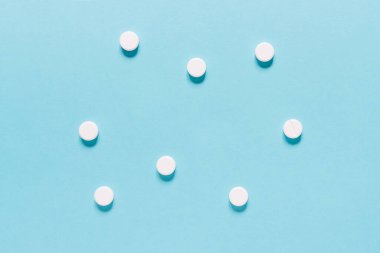 Scattered white pills on blue background. Mock up for special offers as advertising, web background or other ideas. Medical, pharmacy and healthcare concept. copyspace. Empty place for text or logo