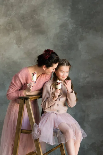 Mom and daughter in pink sweaters and pink skirts hold cakes in their hands. Happy mother\'s day, girlfriend\'s day.