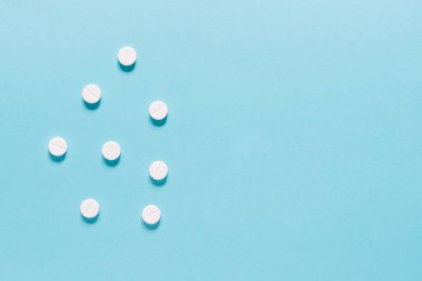Scattered white pills on blue background. Mock up for special offers as advertising, web background or other ideas. Medical, pharmacy and healthcare concept. copyspace. Empty place for text or logo