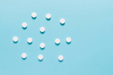 Mavi üzerine ilaç hapları. Eczane ve tıbbi konseptli beyaz yuvarlak hapları kapatın. Düz yatış, üst görünüm. 