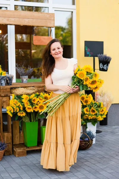 カフェの近くにひまわりの花束を持つエレガントな大人の女性 — ストック写真
