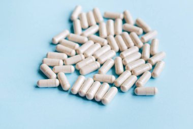 Mavi üzerine ilaç hapları. Eczane ve tıbbi konseptli beyaz yuvarlak hapları kapatın. Düz yatış, üst görünüm.