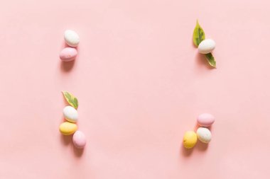 Mutlu Paskalya dekorları. Boş tebrik kartı, davetiye maketi. Şenlikli pastel pembe arka plan, Paskalya yumurtası şeklinde çikolatalar. Boşluğu kopyala, düz yat, üst görünüm.