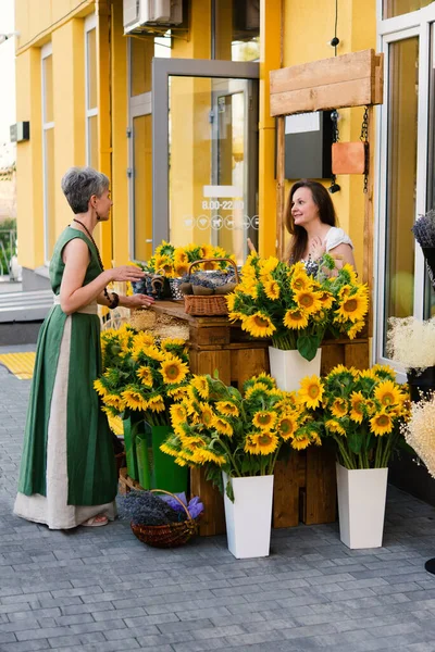 大人2人の笑顔の女性 カフェの近くにひまわりの花束を持つエレガントな女性 — ストック写真