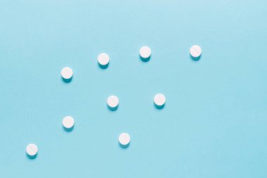 Mavi üzerine ilaç hapları. Eczane ve tıbbi konseptli beyaz yuvarlak hapları kapatın. Düz yatış, üst görünüm.