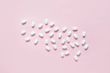 Pembe üzerine ilaç hapları. Eczane ve tıbbi konsepti olan büyük beyaz hapları kapat. Düz yatış, üst görünüm.