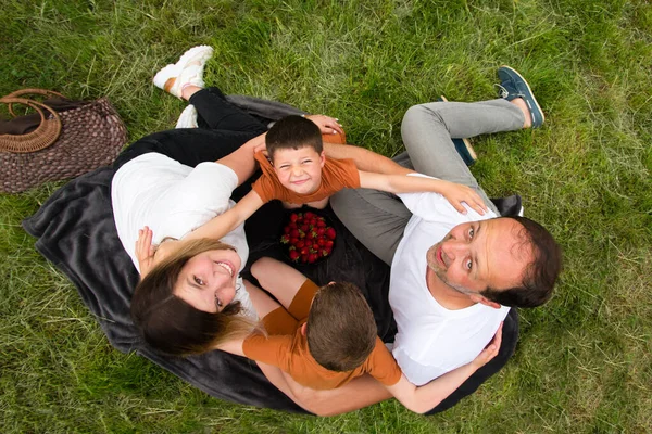 Family hugs. Mom, dad and kids on a picnic.  Sitting  on the grass on a blanket and hug. Family day. Happy parenting. Mother\'s Day and Father\'s Day.