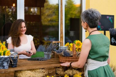 Two adult smiling women. Elegant woman with a bouquet of sunflowers flowers near a cafe - a flower shop. clipart