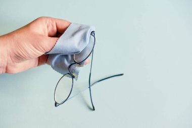 hand wipes glasses with a napkin on a blue background. Glass cleaning cloth, napkin