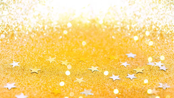 Golden holiday background. Merry Christmas and Happy New Year. Colorful of confetti stars and bokeh lights on golden background. Brilliant colored sequins. Holiday greeting card.