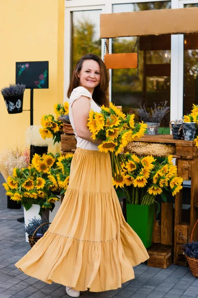 カフェの近くにひまわりの花束を持つエレガントな笑顔の女性 — ストック写真