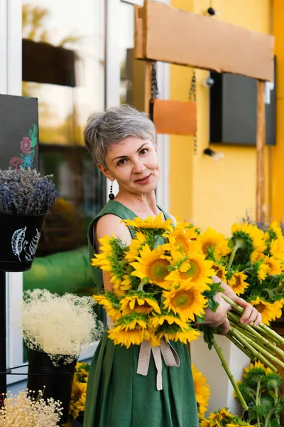 カフェの近くにひまわりの花束を持つエレガントな笑顔の女性 — ストック写真