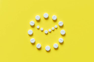 Sarı arka planda beyaz yuvarlak haplar. İzle. İlaç alma zamanı. İlaç almak için açık program.