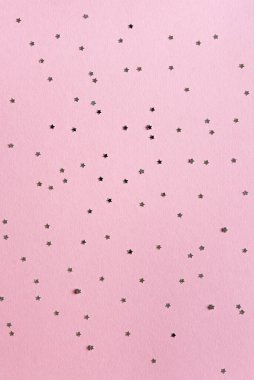 Tatil tebrik kartı. Noel, yeni yıl partisi sahnesi. Gümüş yıldızlı, parlak konfeti şekilli ve boş bir yer. Pembe kağıt arkaplan.