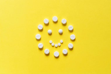 Sarı arka planda beyaz yuvarlak haplar. D vitamini, güneş. Neşeli gülen adam. Mutluluk vitaminleri. Boşluğu kopyala, üst görünüm, maket.