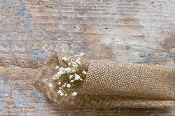 Eski Ahşap Arka Planda Kaba Bir Kumaş Üzerinde Beyaz Çiçekler — Stok fotoğraf