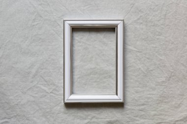 Keten masa örtüsü arkaplanındaki boş beyaz çerçevenin yakınlaştırılması. Düz yerde, üst tarafta. Bahar, yaz düğünü, doğum günü, anneler günü, aile, taklit sahnesi.