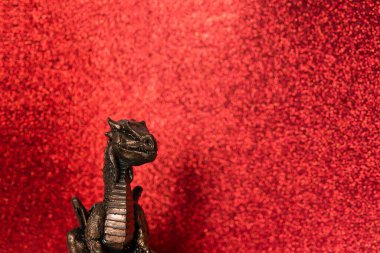 Kırmızı parıltılı arka planda bronz ejderha. Noel kartı. Çin Yeni Yılı 2024 Ejderha heykeliyle