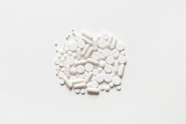 Beyaz bir masaya dağılmış beyaz haplar. Reklam, web geçmişi ya da diğer fikirler için özel teklifler alın. Tıbbi, eczane ve sağlık hizmetleri konsepti. çoklu uzay. Metin veya logo için boş yer