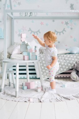 Küçük kız, çocuk odasındaki masada tahta küpler yapımcısıyla oynuyor. Anaokulu, eğitim oyunları.