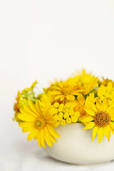 Floral minimalism greeting card. Bright yellow flowers in a round vase on a table with a white tablecloth. Happy mother's day, women's day or birthday pastel colors background.