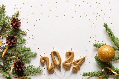 Yeni yılın kutlu olsun. Noel ağacı dalları ve 2024 numaralı altın mumlu Noel kartı afişi, koniler ve altın dekoratif kurdele, altın yıldızlar. Hafif arkaplan. maketleme.