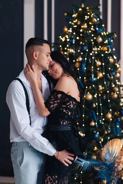 Portrait of a young couple in their living room at christmas eve.Lovely couple in love embracing near christmas tree