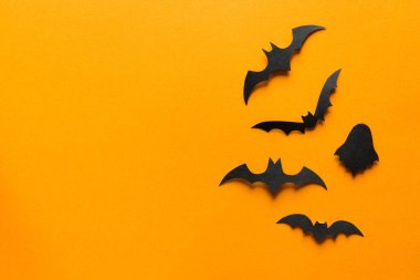 Cadılar Bayramı süslemeleri, turuncu arka planda uçan hayaletlerdeki kağıt yarasalar. Fotokopi alanı olan Cadılar Bayramı partisi tebrik kartı modeli. Cadılar bayramı konseptin kutlu olsun. Düz yatış, üst görünüm