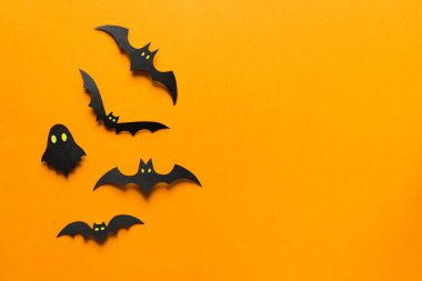 Cadılar Bayramı süslemeleri, turuncu arka planda uçan hayaletlerdeki kağıt yarasalar. Fotokopi alanı olan Cadılar Bayramı partisi tebrik kartı modeli. Cadılar bayramı konseptin kutlu olsun. Düz yatış, üst görünüm