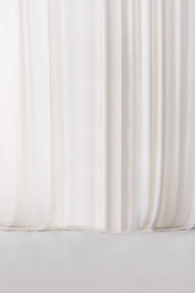White or light gray curtain fabric texture and background. Large wall curtain. Curtain for hotel presentations. Cream colored cloth.