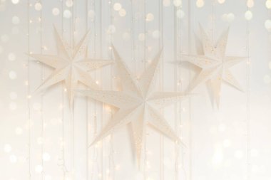 Noel yıldızı lambası. Romantik ve samimi bir kart. Yıldız şeklinde dekoratif lambalar ve ampullü çelenkler. Noel dekoru ve bokeh arkaplanı.