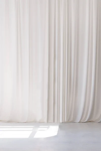 White curtain that dropped down as a straight line. White wooden floor. Background for inserting text, empty spaces.