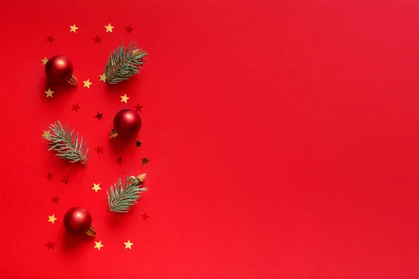 Kırmızı Noel geçmişi. Kırmızı noel ağacı, kırmızı noel baloları, altın yıldız süslemeleri ve boş boşluklu çam dalları. Noel Arifesi konsepti.