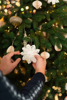 Noel ağacına bir Noel oyuncağı yıldızını süsler ve asar. Süslü dallar, toplar, çelenkler, bokeh. Metin için boşluk içeren kartpostal.