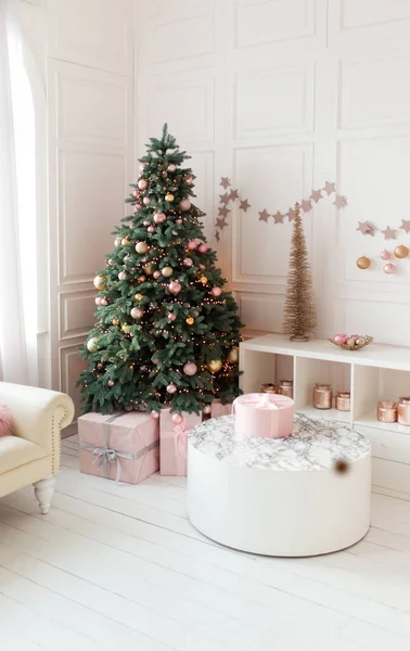 Christmas home interior. White room with a large decorated Christmas tree, gift boxes. Holiday decor.