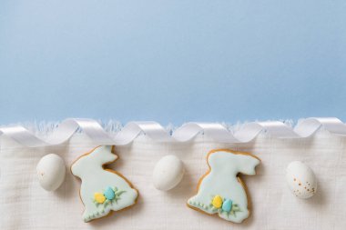 Paskalya 'da ev yapımı zencefilli çörek farklı şekillerde krema ya da tavşan şeklinde kurabiyeler. Beyaz çikolatalar, paskalya yumurtaları. Mavi ve beyaz arkaplan, üst görünüm, boşluk kopyala