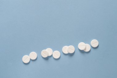 Mavi masaya yayılmış beyaz yuvarlak haplar. Özel teklifler için reklam yapın, internet geçmişi. Tıbbi, eczane ve sağlık hizmetleri konsepti. Metin veya logo için boş kopyalama alanı